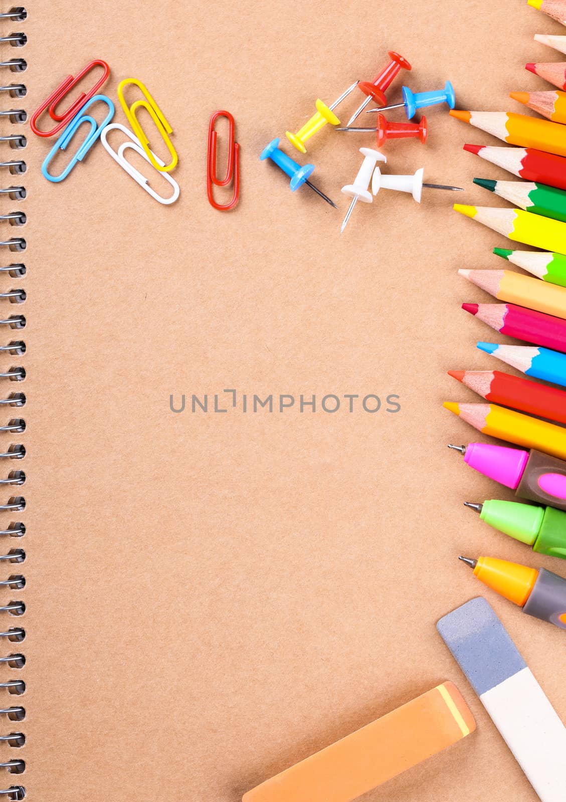 Notebook closeup with colored pencils, erasers, paperclips and buttons