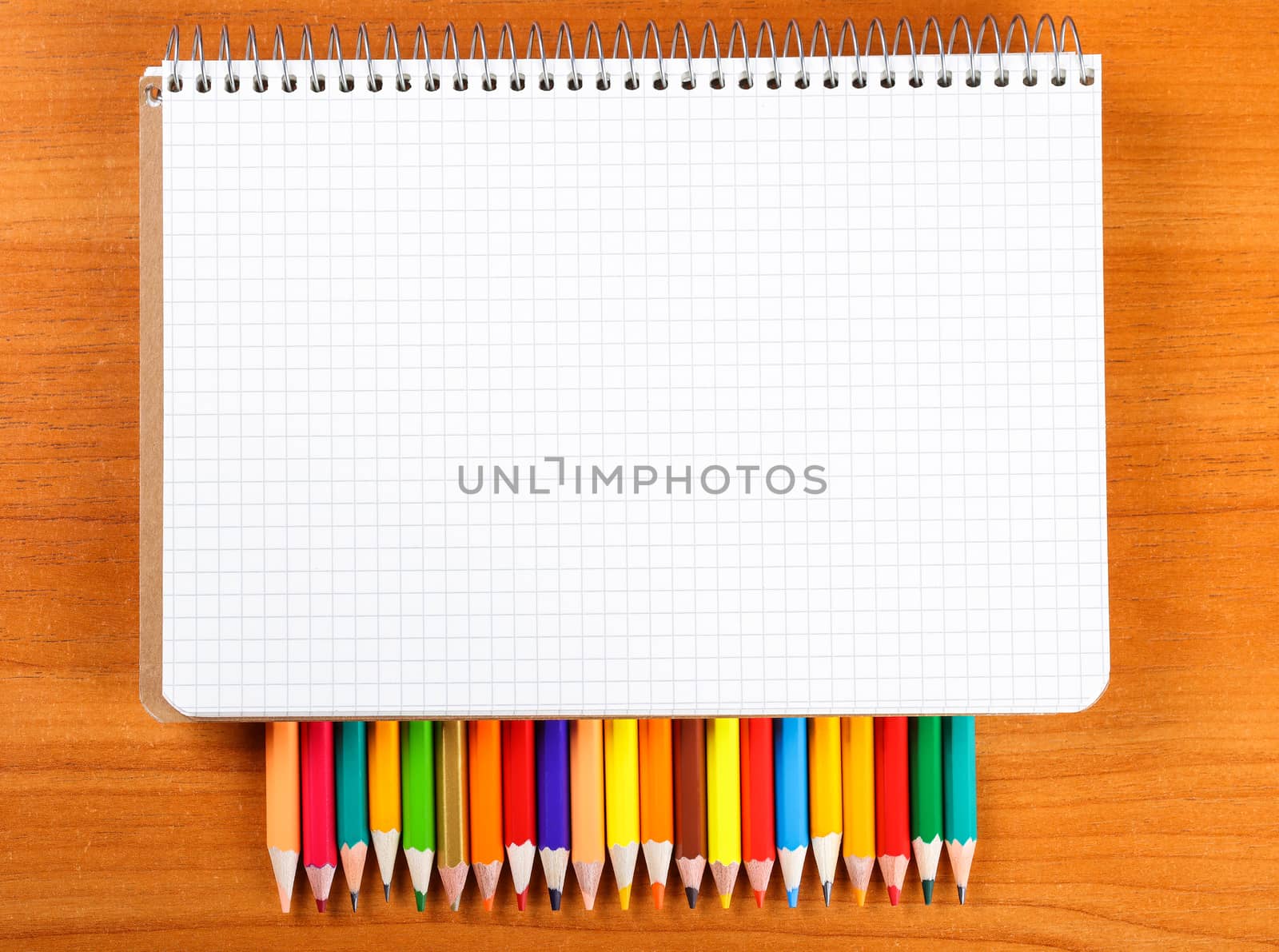 notebook and a set of colored pencils on wooden background