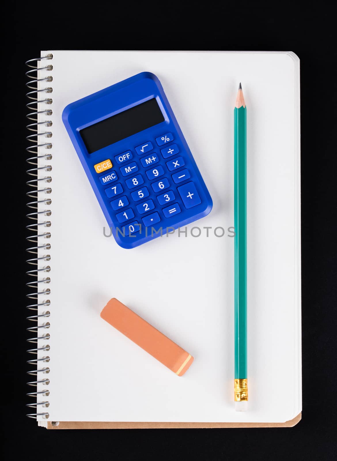 notebook, calculator, eraser and pencil on a black background