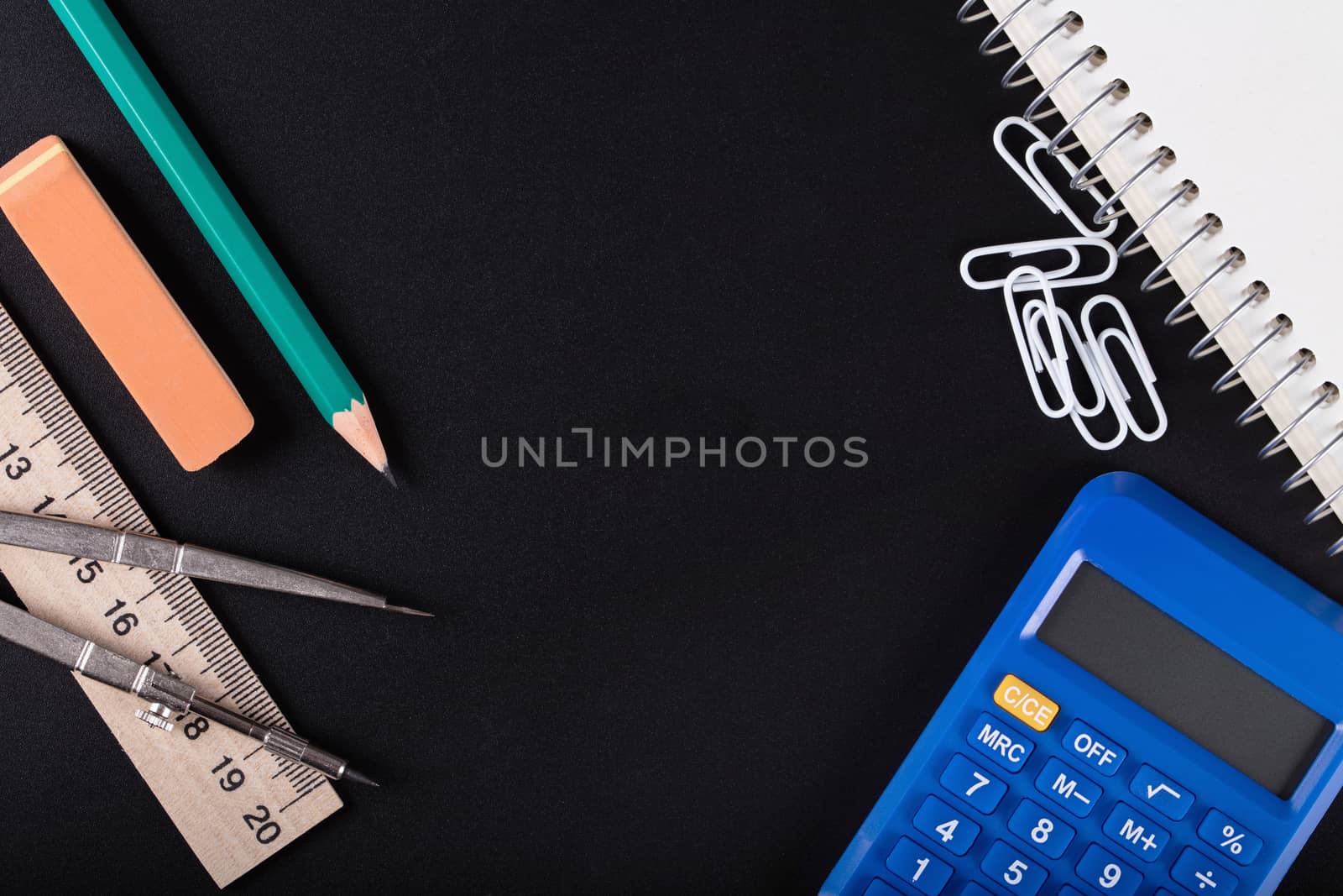 notebook, calculator, eraser, ruler, compass and pencil on a black background