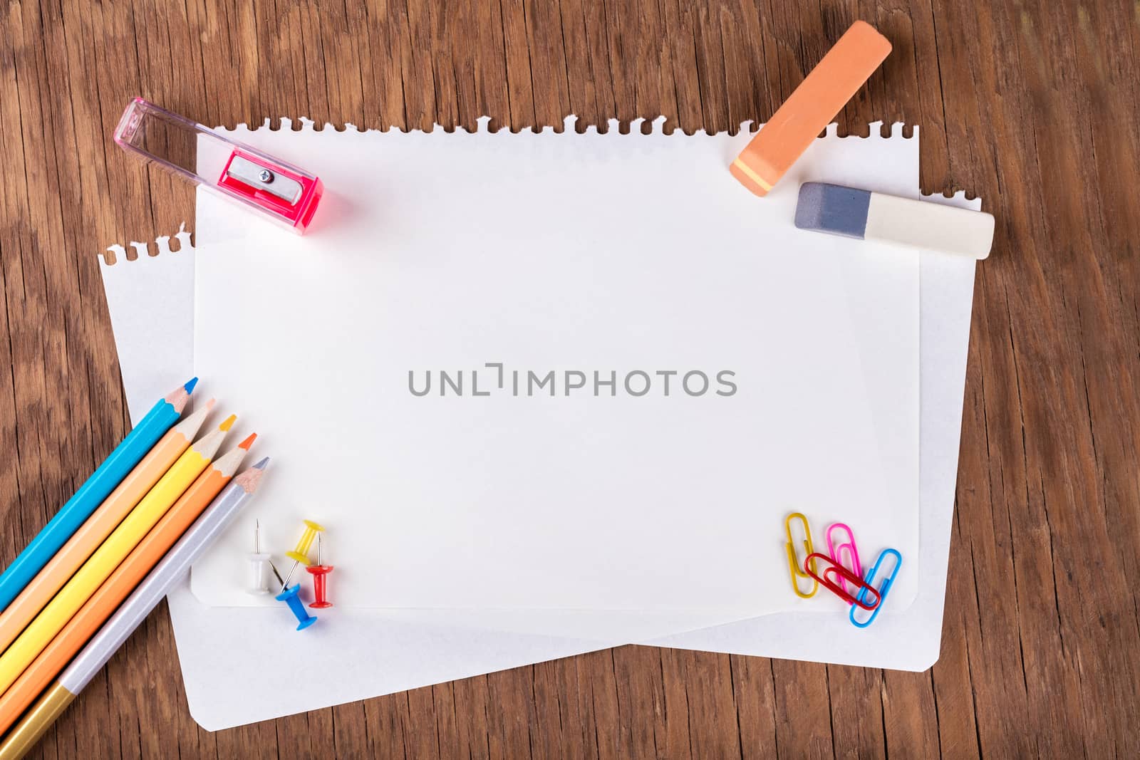 colored pencils with sheets of paper, paperclips, buttons, eraser and sharpener