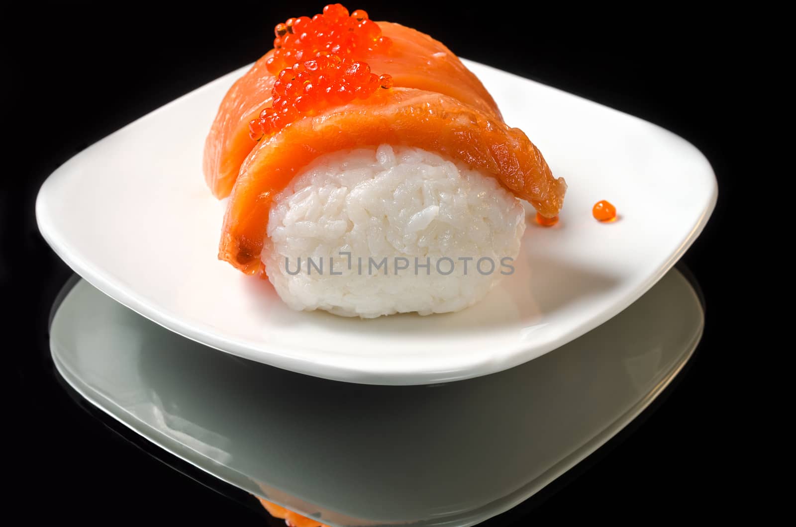 Sushi with salmon and caviar on a white plate and black background with reflection