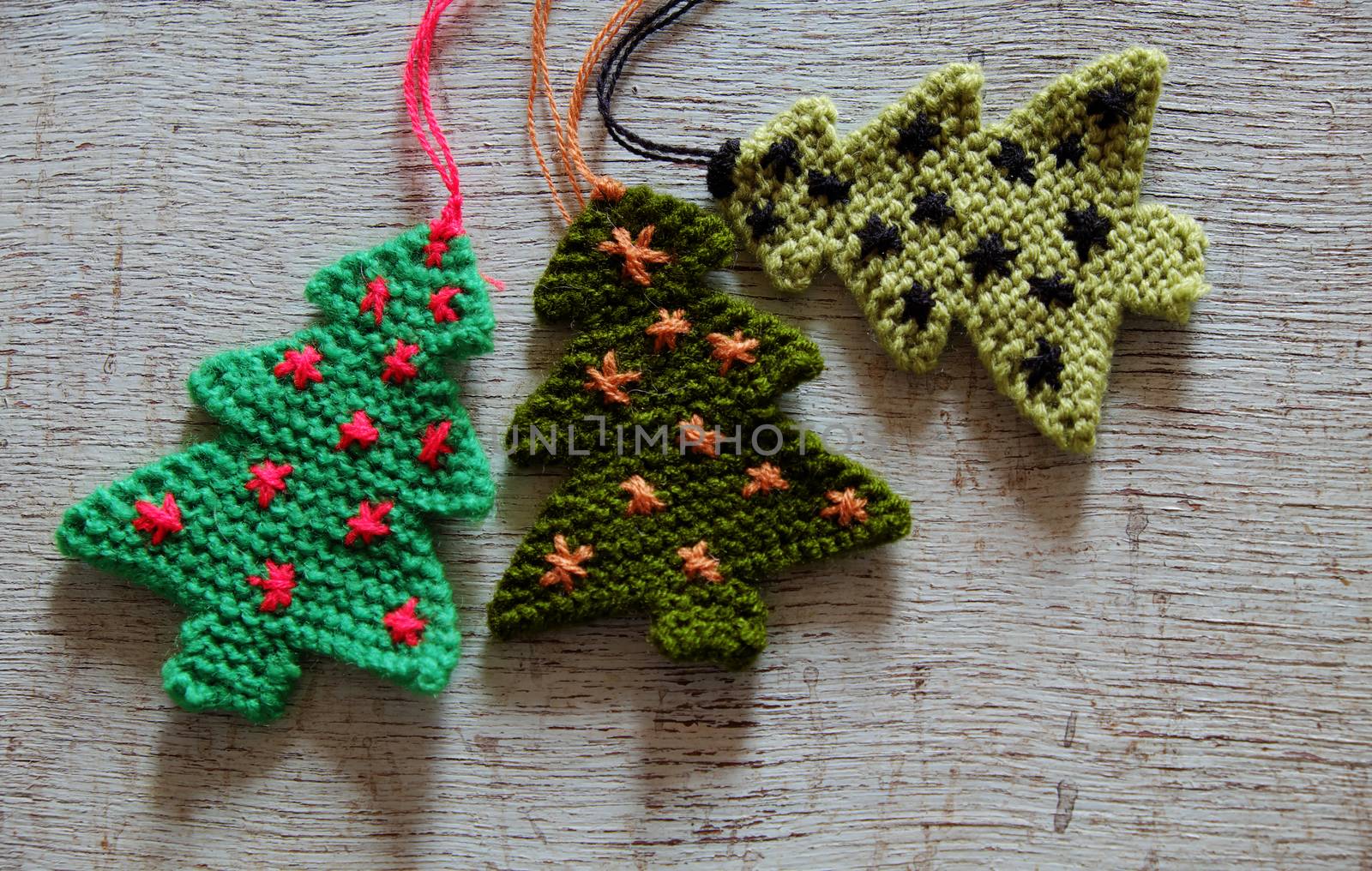 Knitted xmas tree on wooden background, Christmas trees knit from green yarn for holiday season