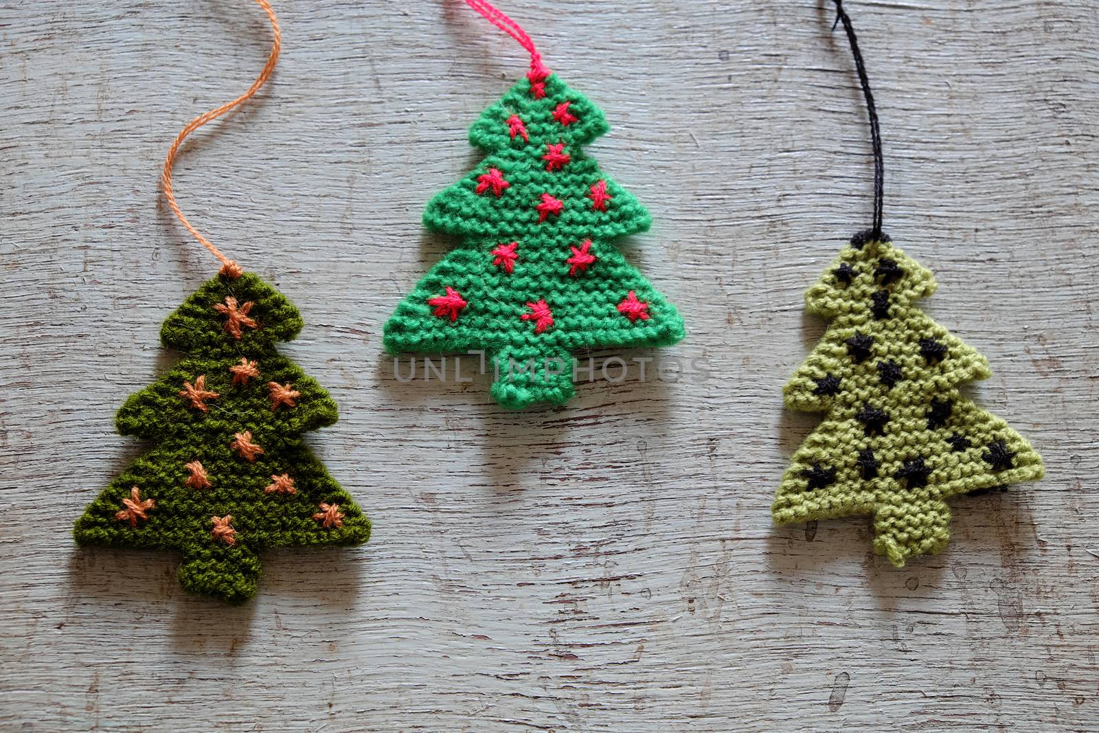 Knitted xmas tree on wooden background, Christmas trees knit from green yarn for holiday season