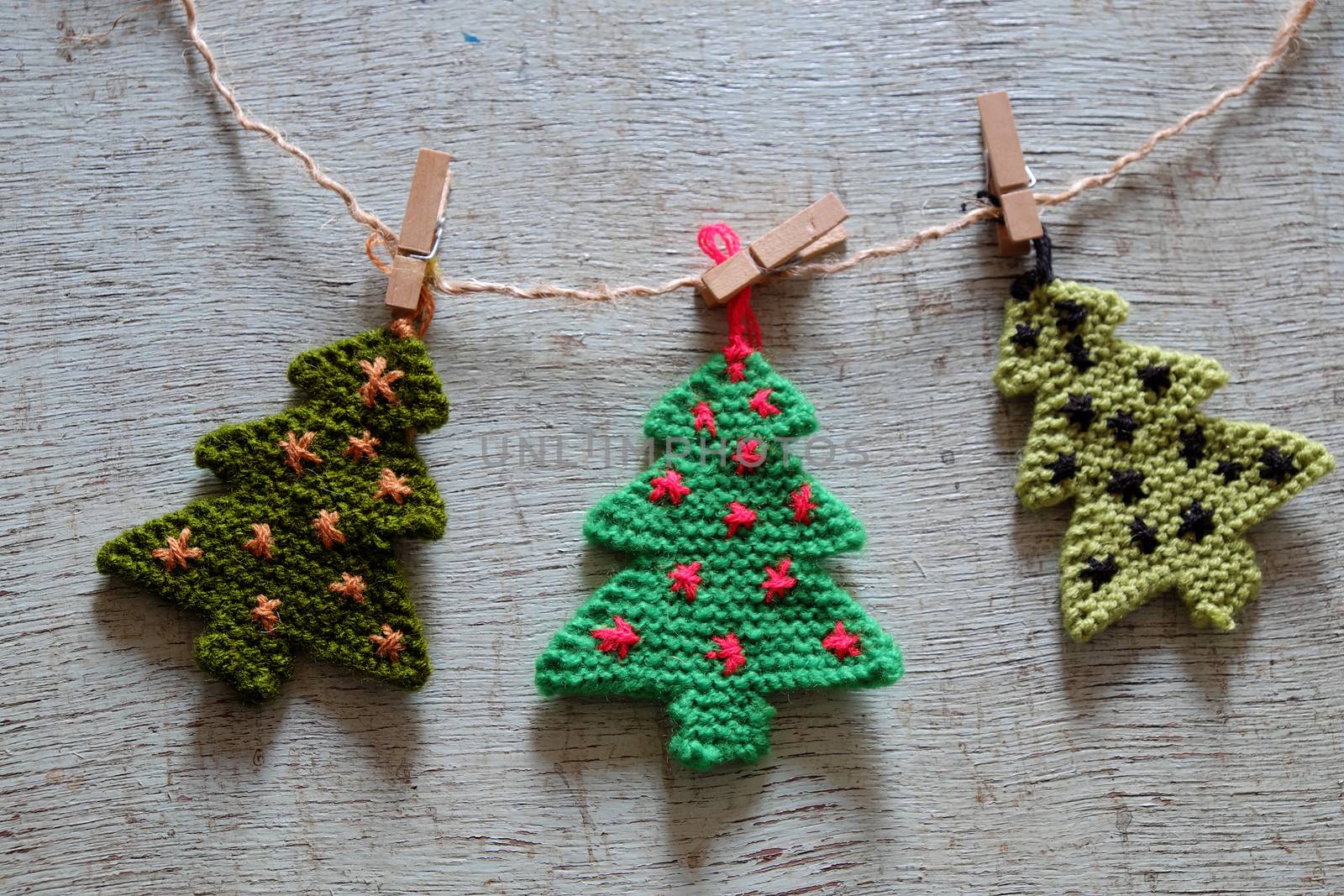 Knitted xmas tree on wooden background, Christmas trees knit from green yarn for holiday season