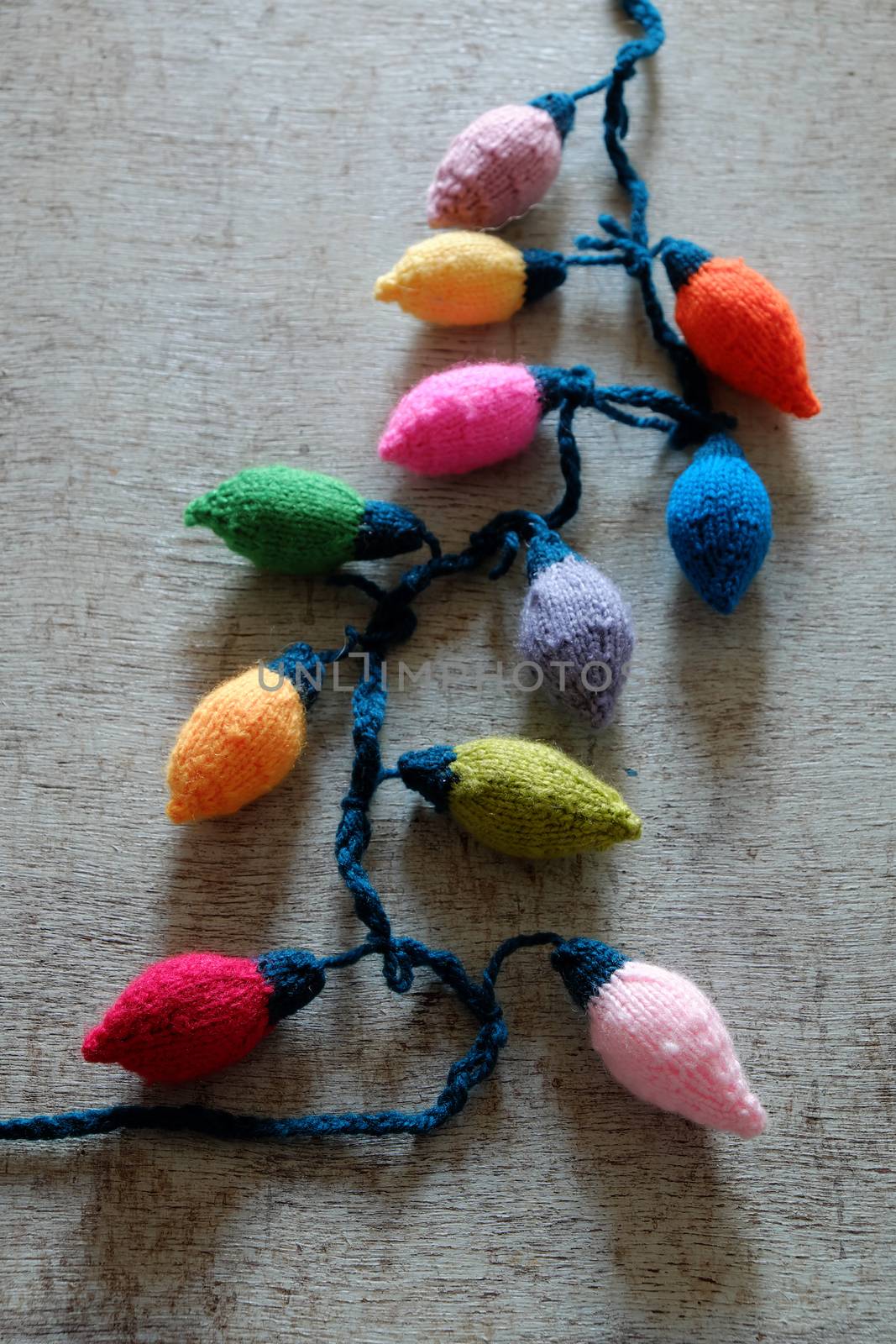Group of colorful Xmas ornament for winter holiday, handmade product from yarn, knitted Christmas lights bulb on wood background