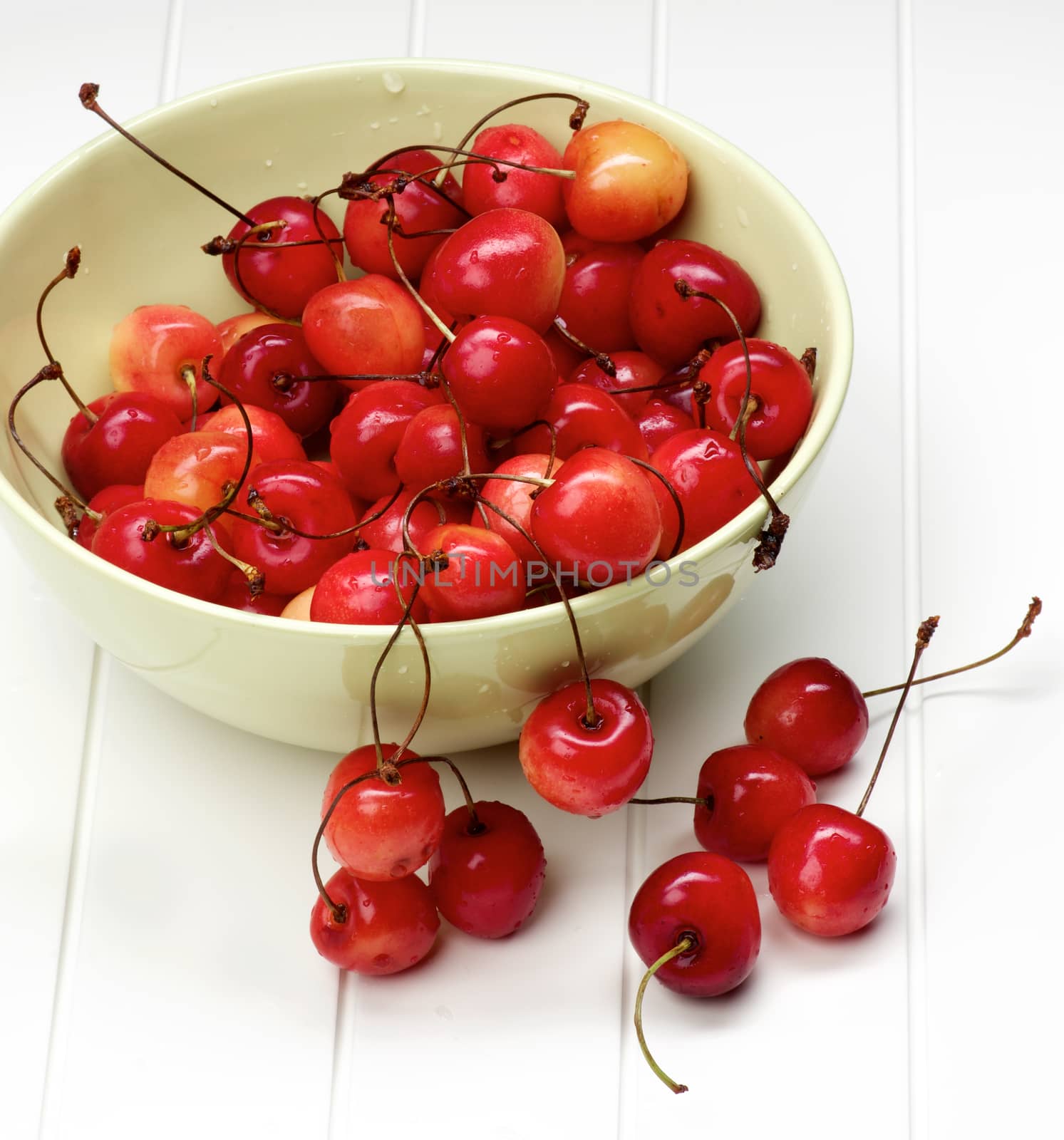 Heap of Fresh Ripe Sweet Maraschino Cherries in Green Bowl closeup on Plank White background