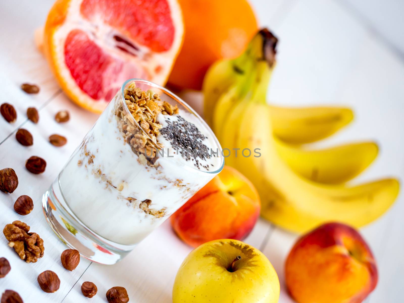 Healthy breakfast: yogurt with muesli and chia seeds, fruits and nuts on white wooden background. Dieting, healthy lifestyle concept meal