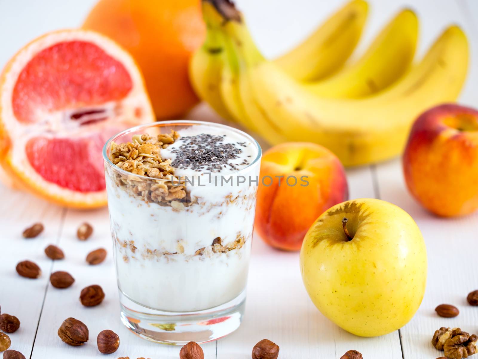 Healthy breakfast: yogurt with muesli and chia seeds, fruits and nuts on white wooden background. Dieting, healthy lifestyle concept meal