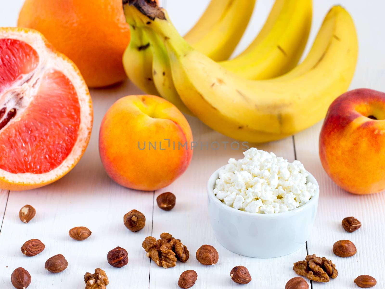 Healthy breakfast: cottage cheese, fruits and nuts on white wooden background. Dieting, healthy lifestyle concept meal