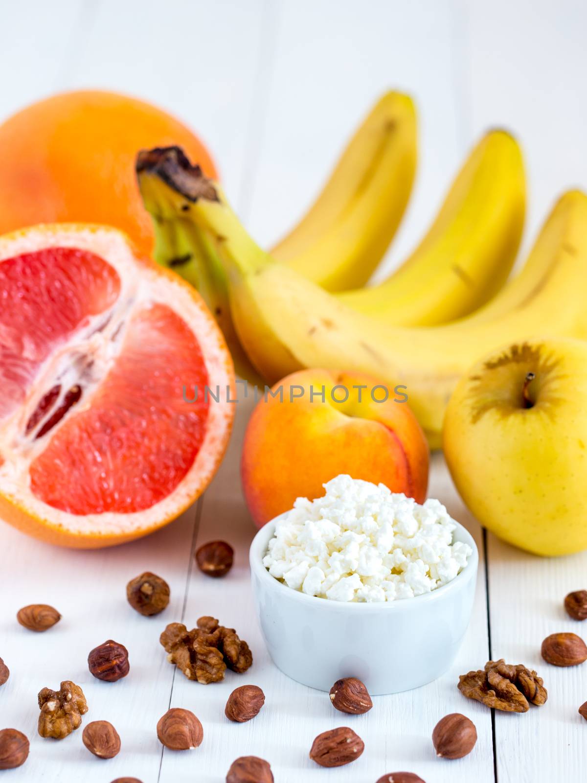 Healthy breakfast: cottage cheese, fruits and nuts on white wooden background. Dieting, healthy lifestyle concept meal. Vertical