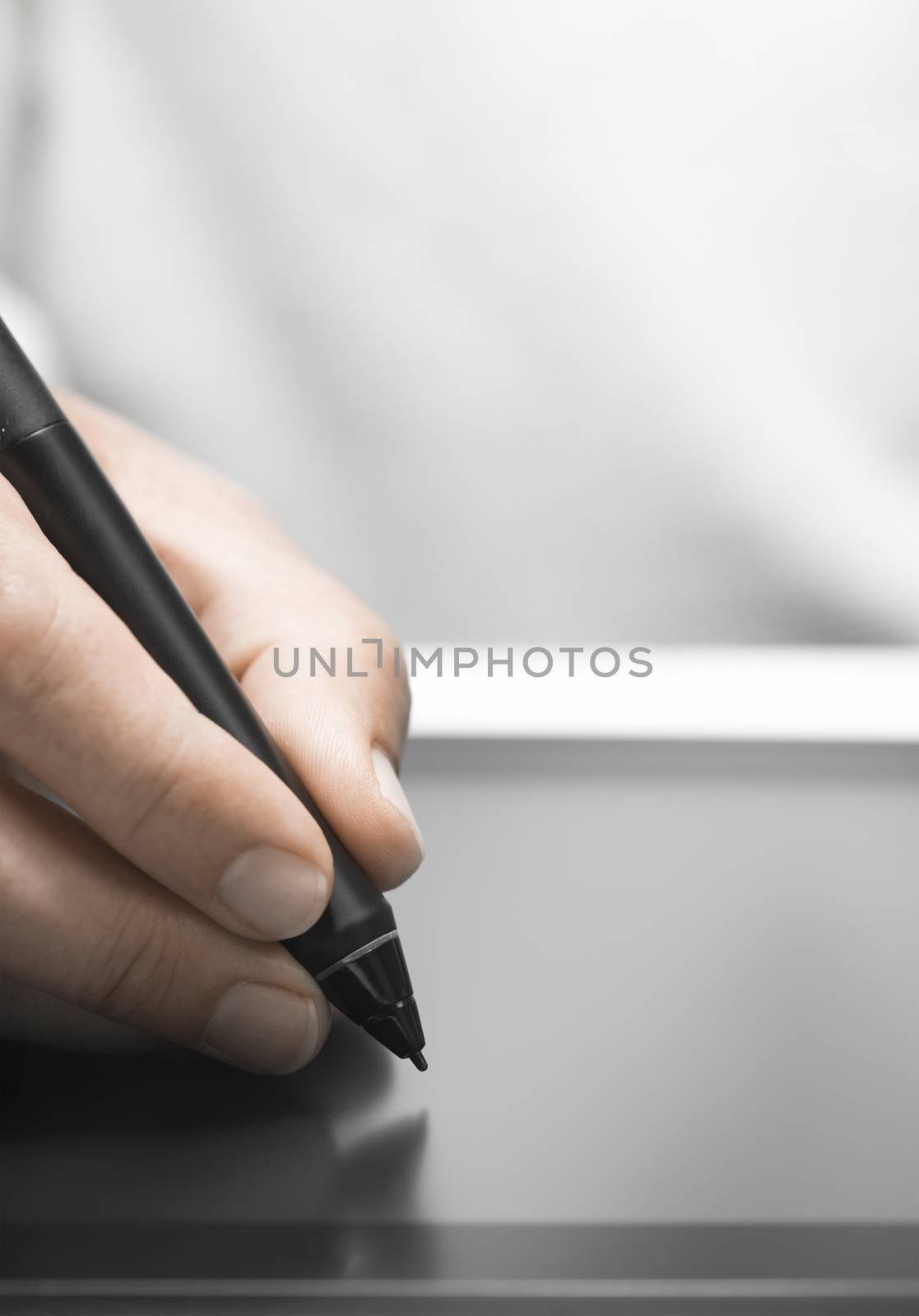 Close up of the hand of a graphic designer holding an electronic stylus. Background with free space for text, vertical image 