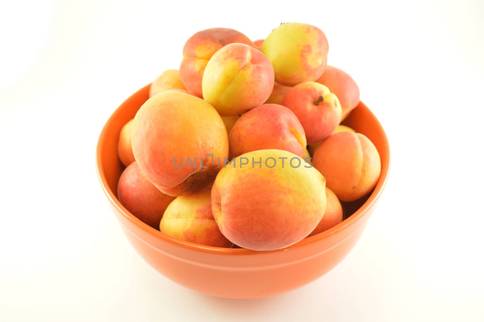 A still life of a bowl full of ripe peaches