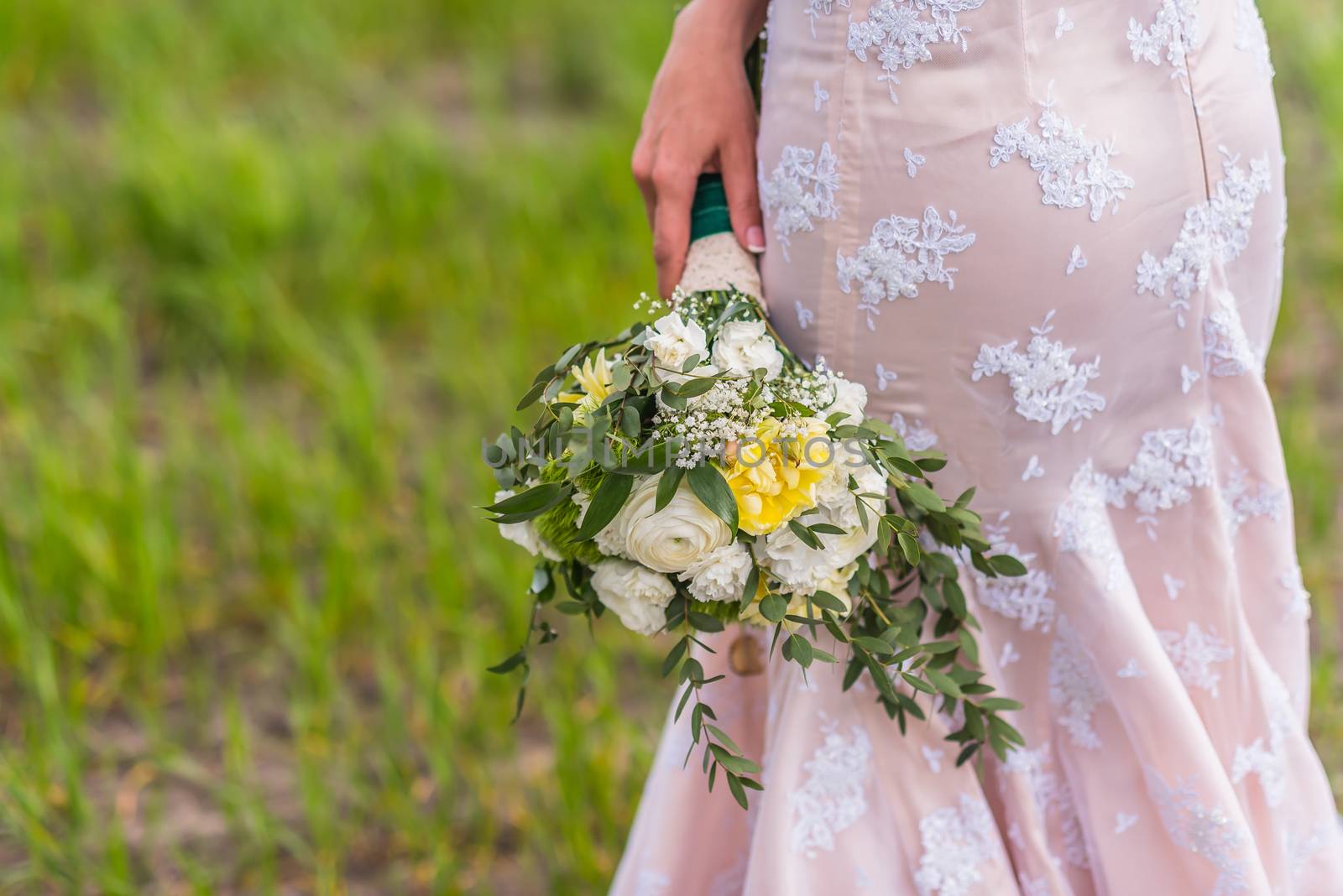 wedding bouquet in hands of the bride on background of the dress