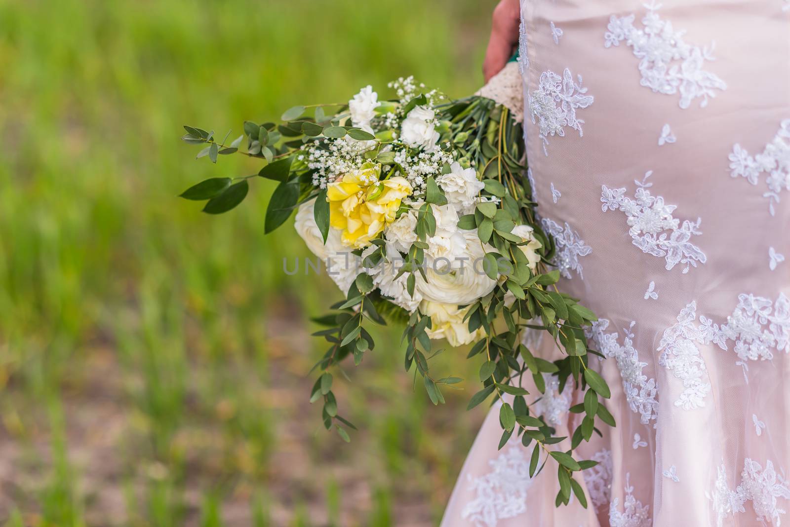 wedding bouquet in hands of the bride on background of the dress