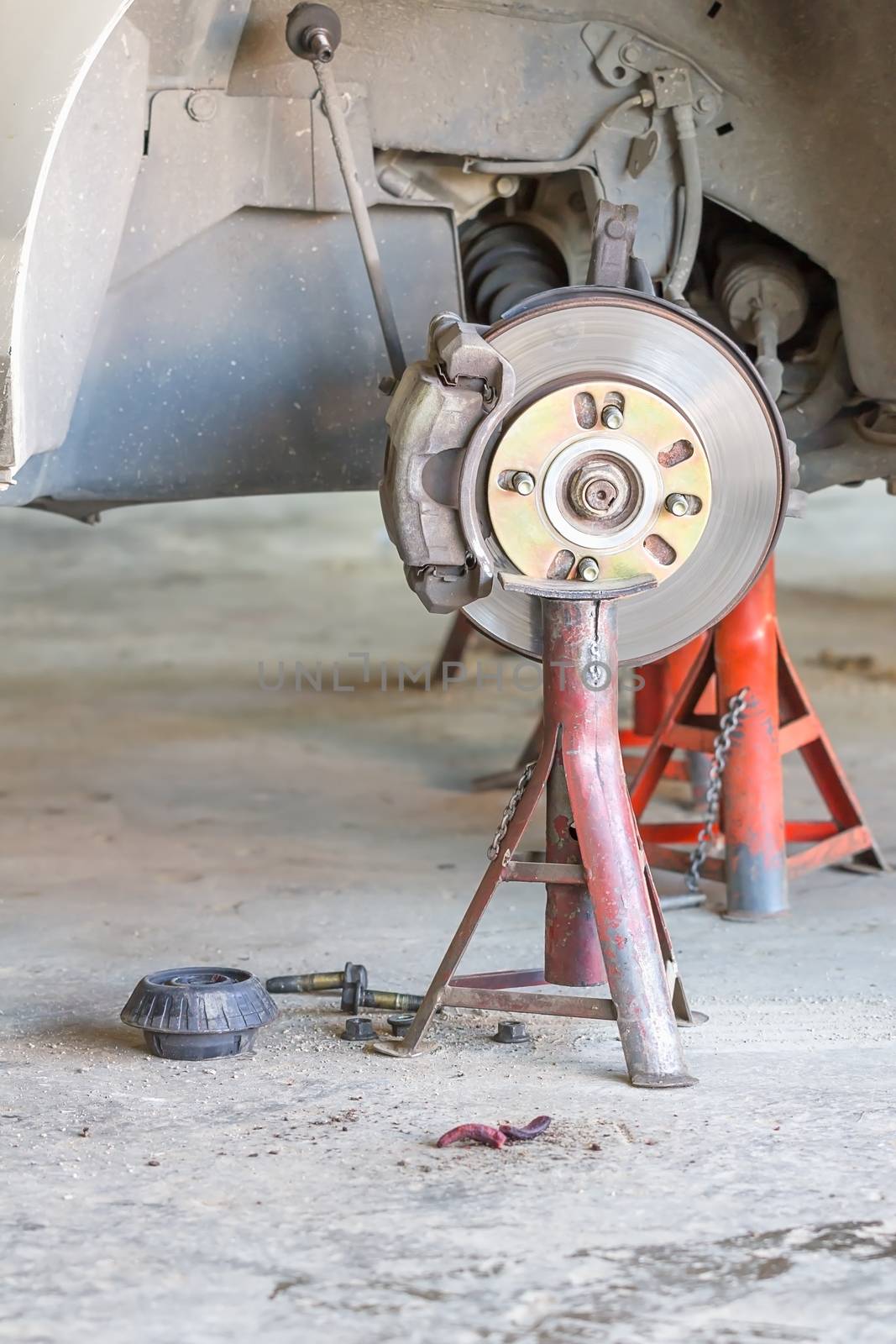 Front disk brake on car in process of damaged tyre replacement. The rim is removed showing the front rotor and caliper.