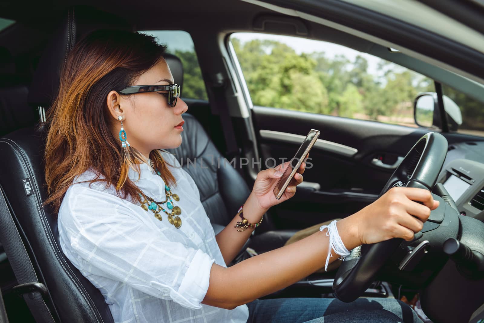 Asian woman looking at a smartphone in the car.