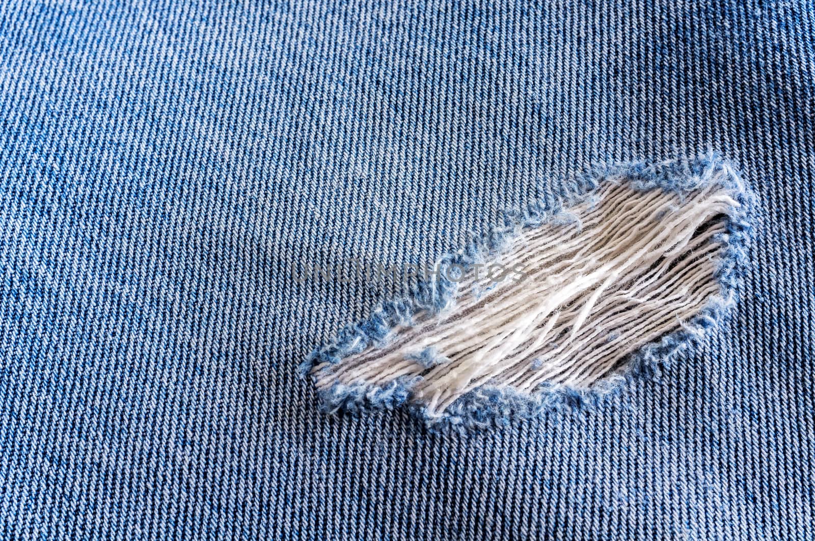 blue jean texture background with a hole and threads showing