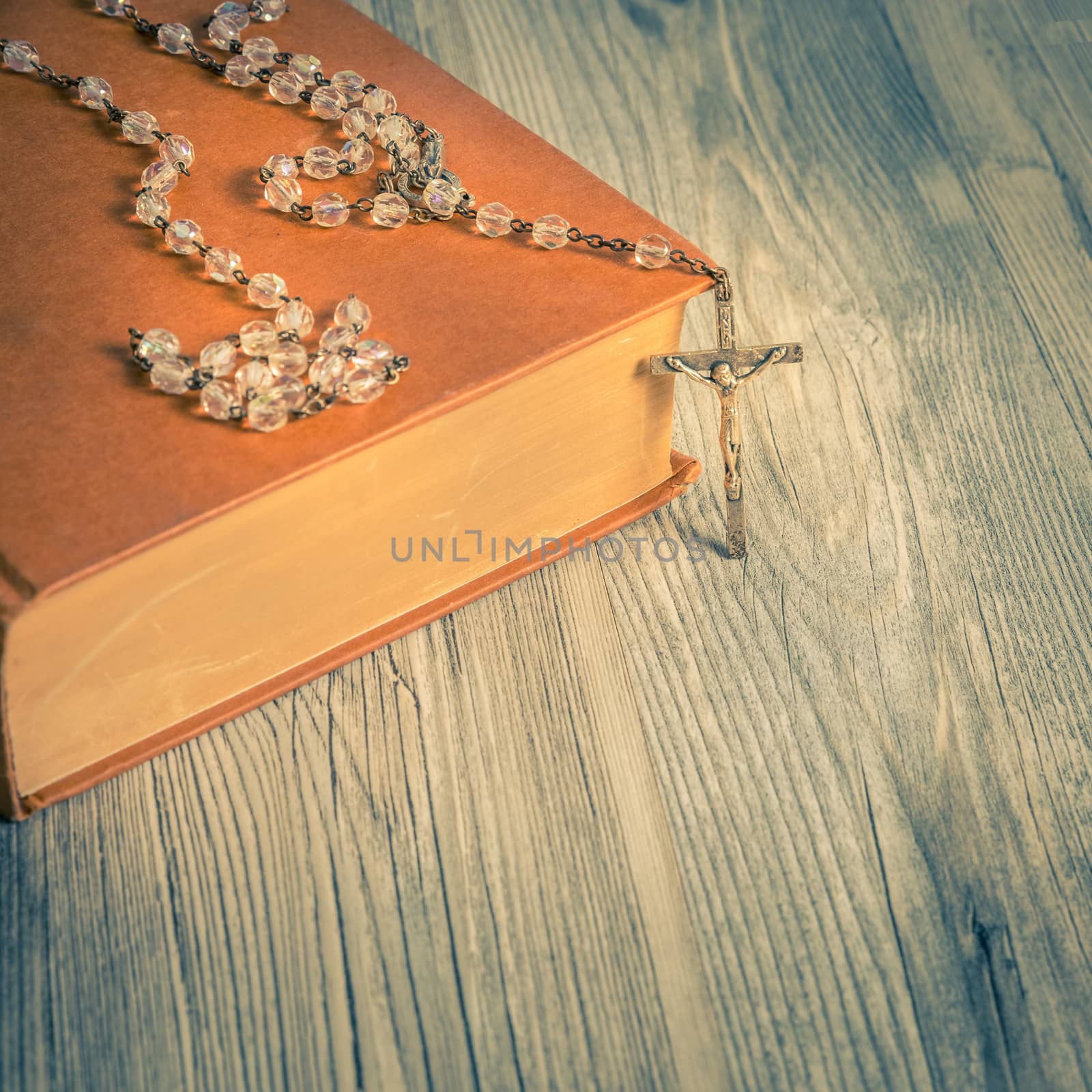 vintage rosary beads on old books, square photo.
