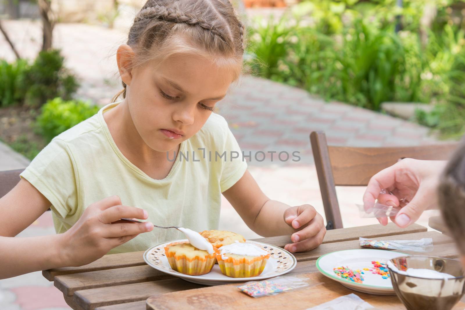 The girl carefully coated with confectionery glaze Easter cupcakes