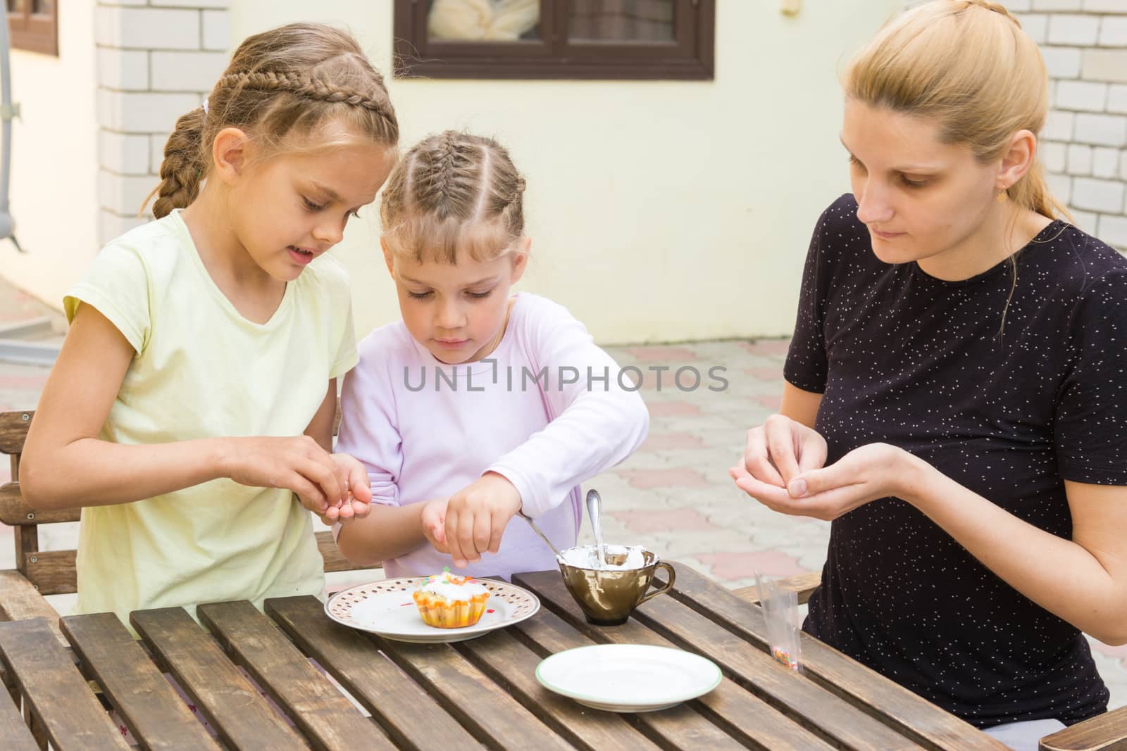 Mother and two daughters are preparing for the holiday Easter cupcakes