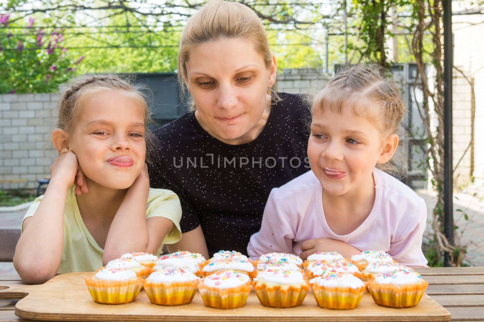 Mother and two daughters salivate looking at freshly Easter cupcakes