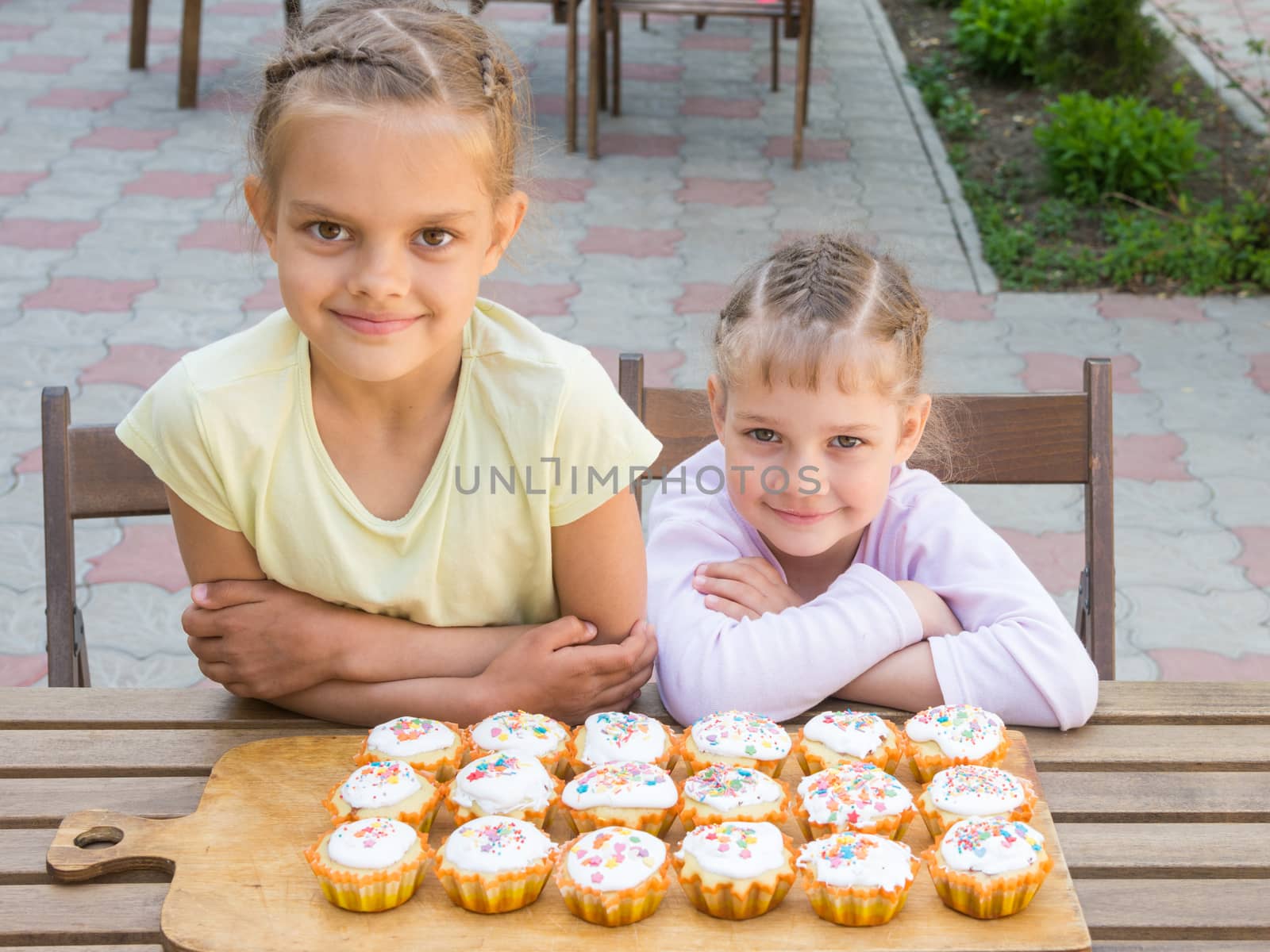 Two sisters sitting at a table on which are freshly baked Easter cupcakes