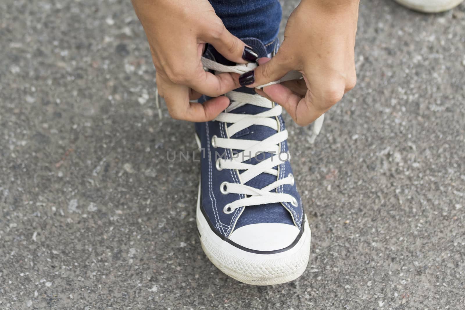 Hands girl with beautiful manicure knotted the laces on your shoelace.