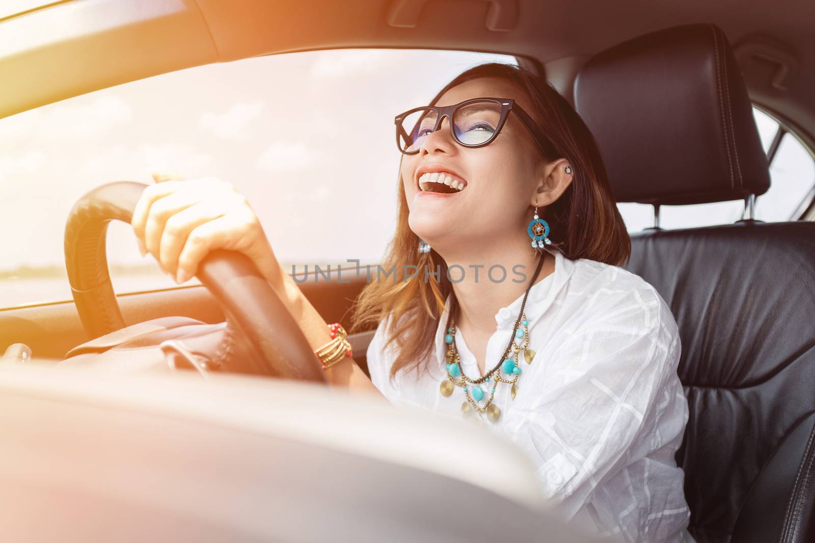 Asian woman driving a car in a happy mood.