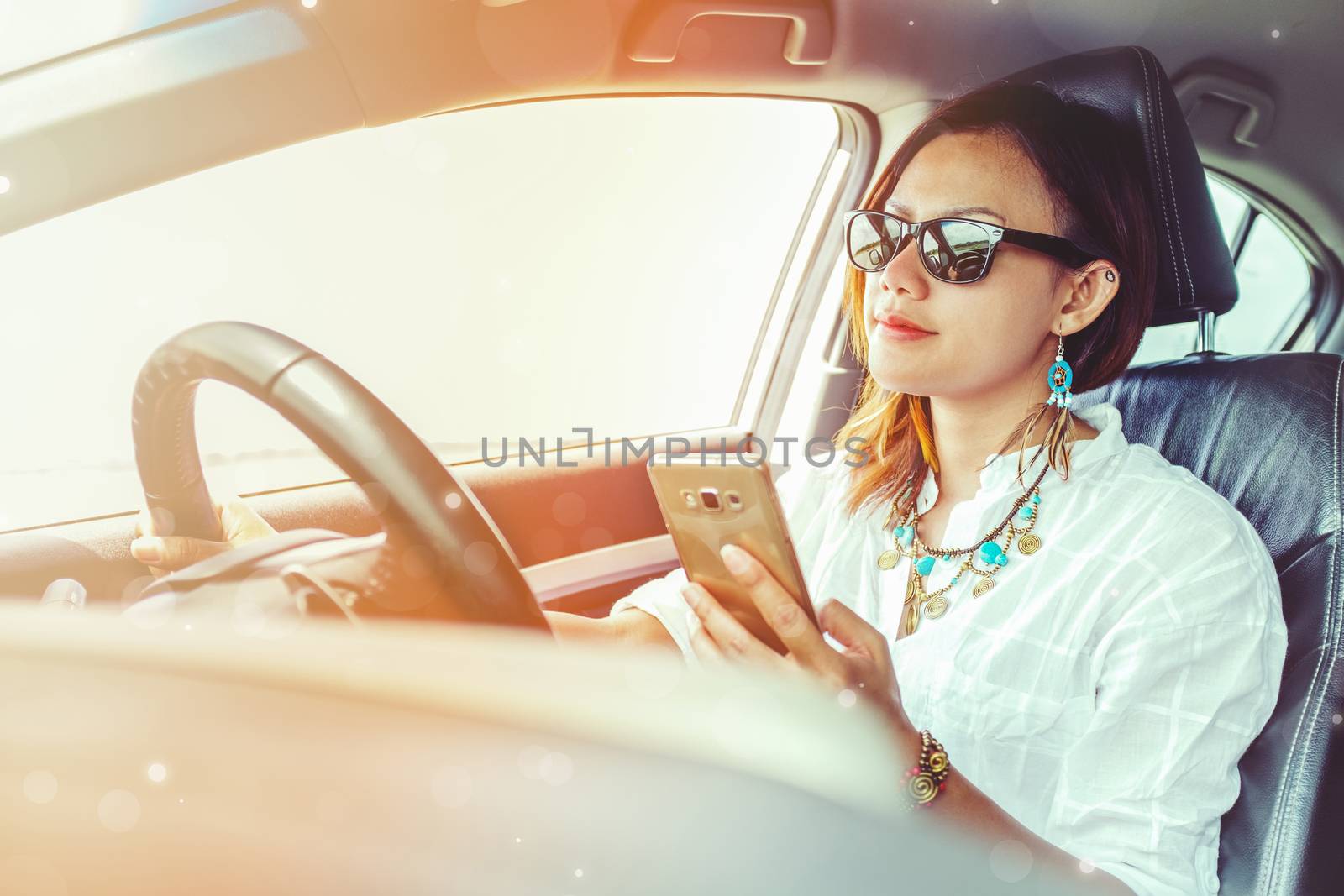 Asian woman looking at a smartphone in the car.