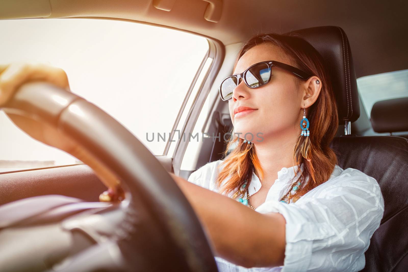 Asian woman driving a car in a happy mood.