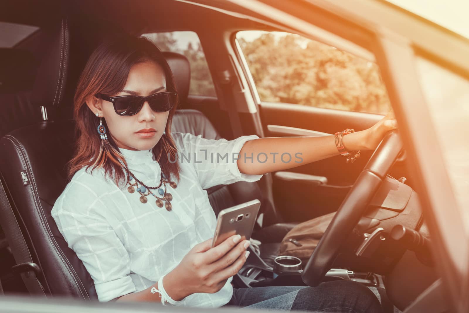 Asian woman looking at a smartphone in the car.