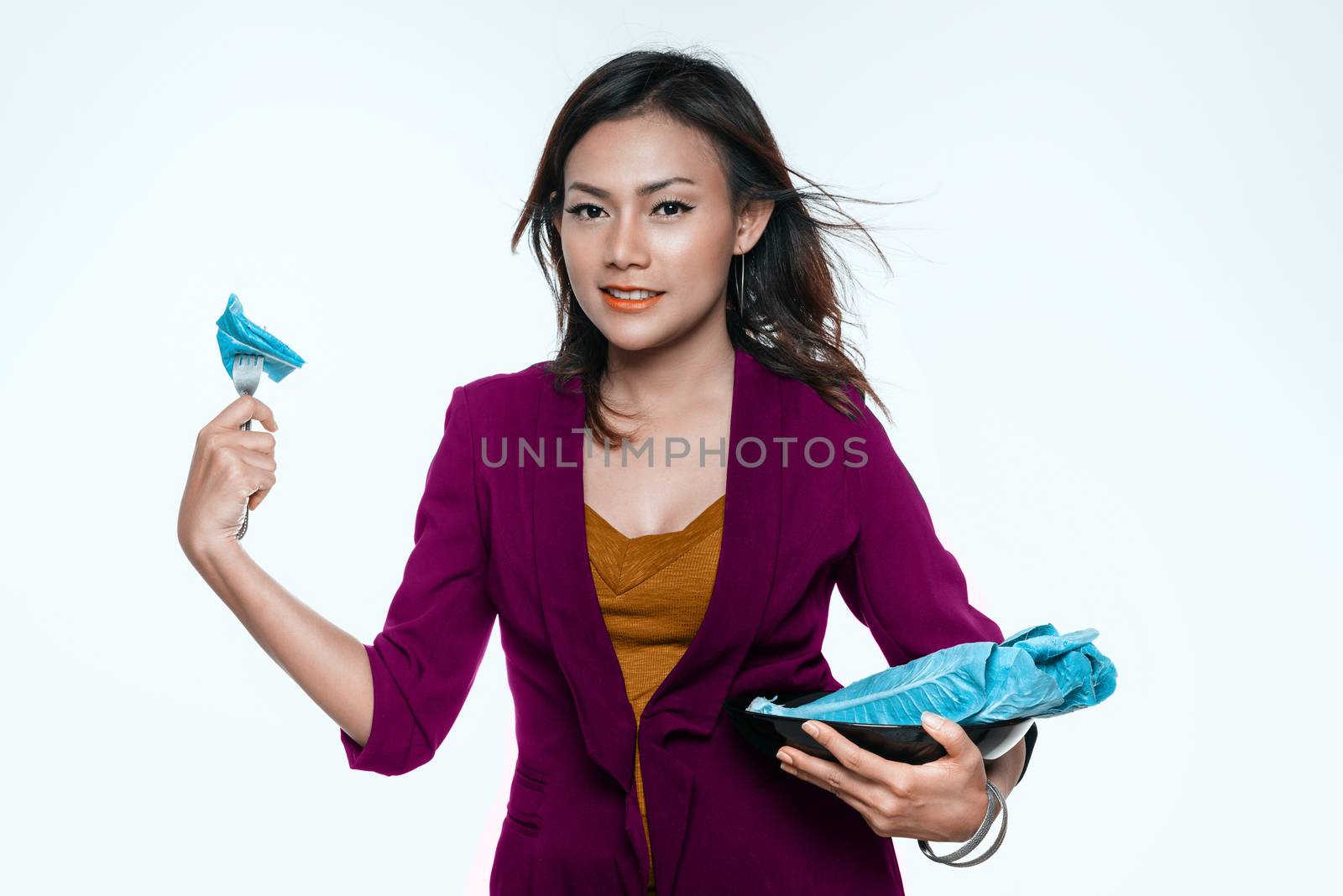 Asian woman eating vegetables, using a fork, happy mood.
