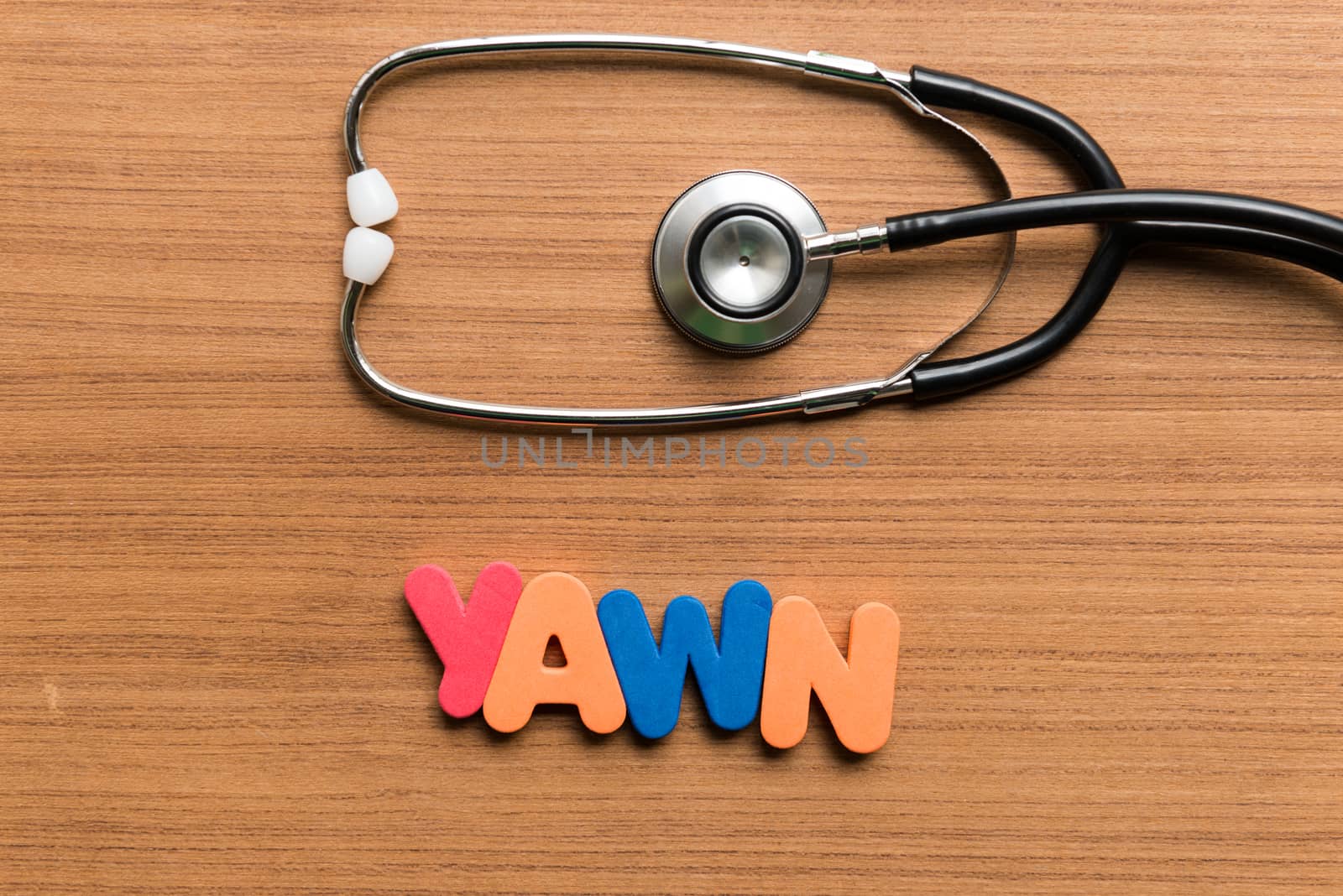 yawn colorful word with stethoscope on wooden background