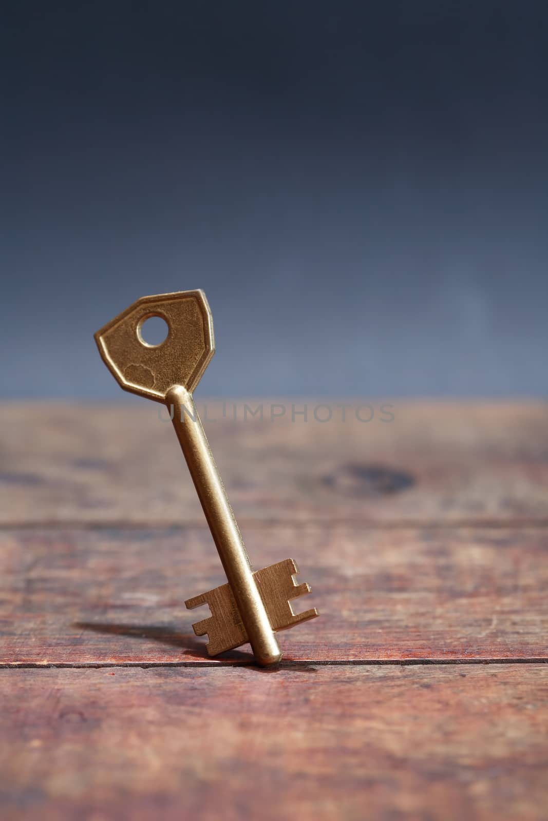 Door key standing on wooden board against dark background