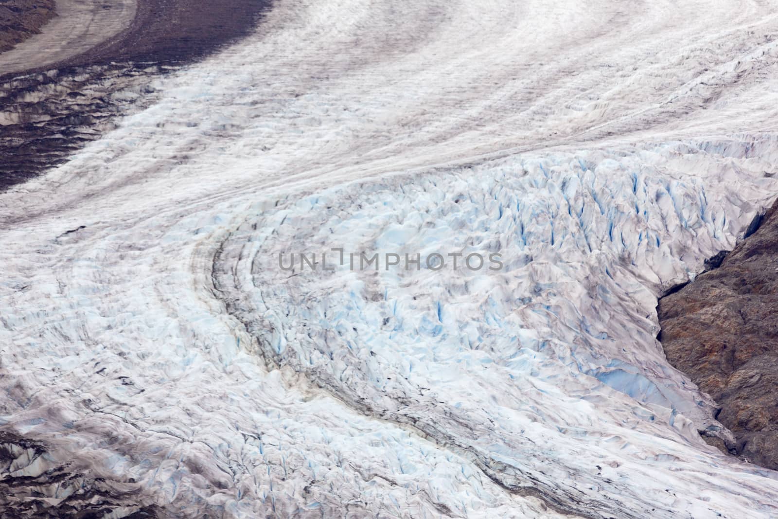 Curving, receding view of Salmon Glacier ice and its exposed rocky ground.  Melt of climate change is visible on fifth largest glacier in North America.  Location is north of Hyder, Alaska, USA, and Stewart, British Columbia on Canadian side of border.  Date taken is September, 2015. 