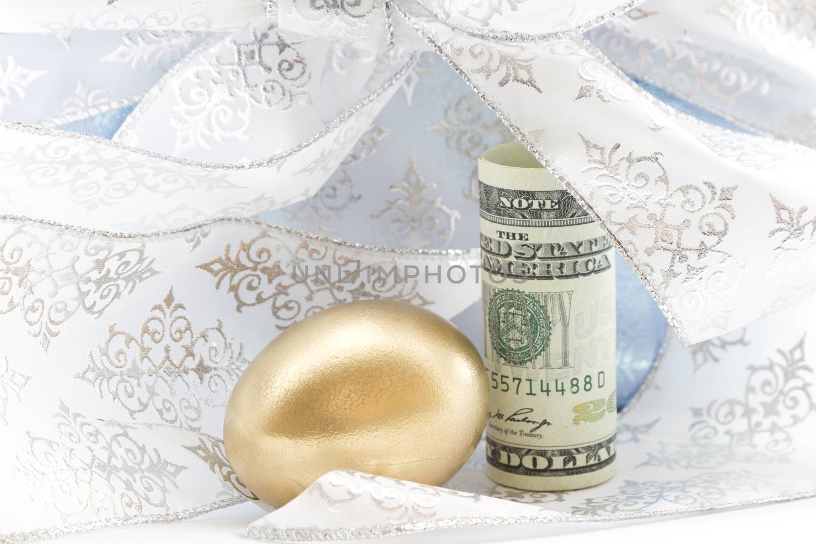 Swirls of silver and light blue ribbon surround gold egg and American dollar.  Generous gifting adds to successful savings.  Retirement joy shows in successful investment planning. 