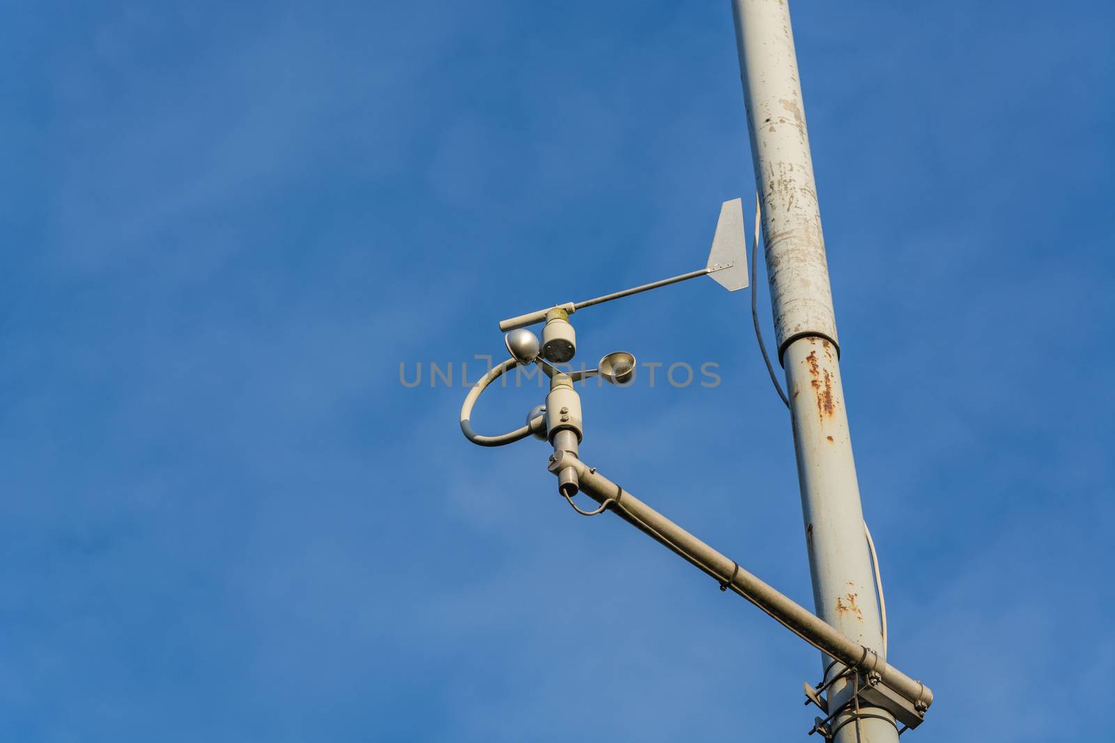 Weather station with anemometer on blue sky.