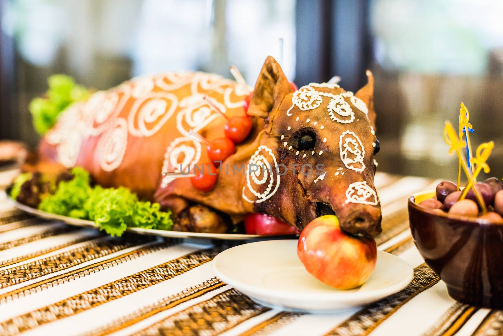 Decorated and roast suckling pig with an apple in his mouth on a white plate on banquet