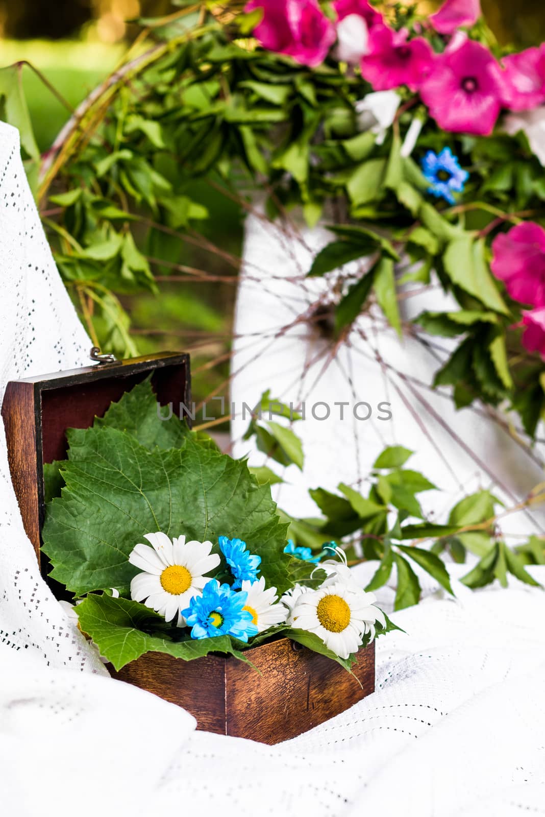 old brown box decorated with camomiles and fresh leaves in a white tablecloth