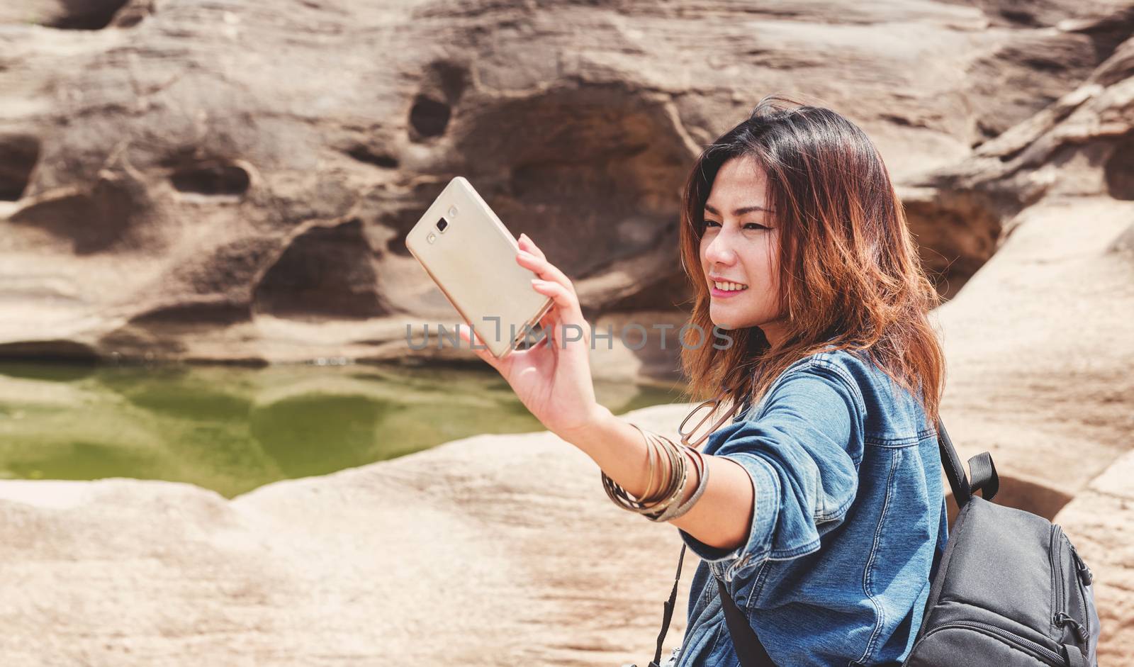 Asia woman taking a photo at Sampanbok natural stone park the grand-canyon of Ubonratchathani Thailand