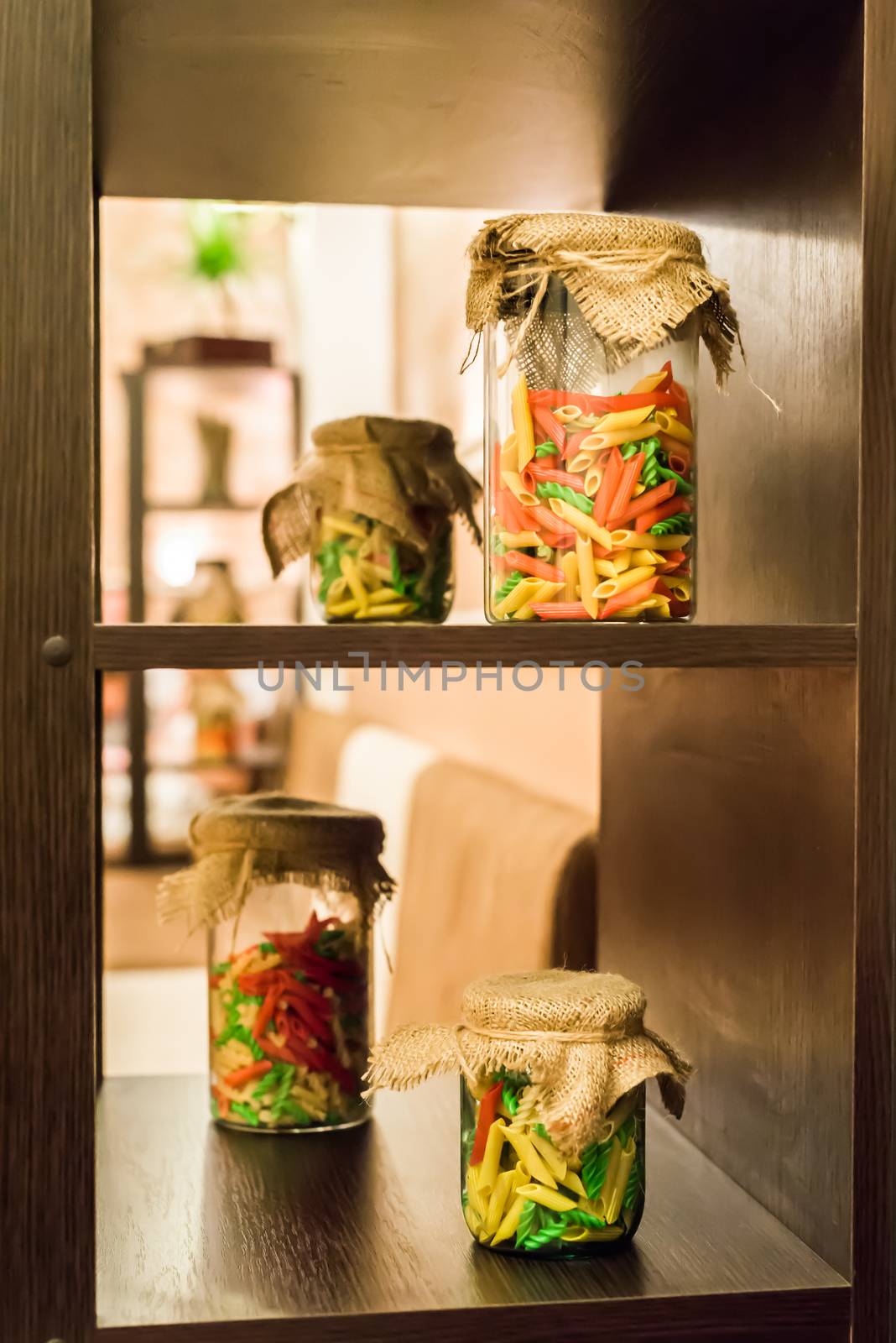 dry colored pasta in glass jars on the shelf