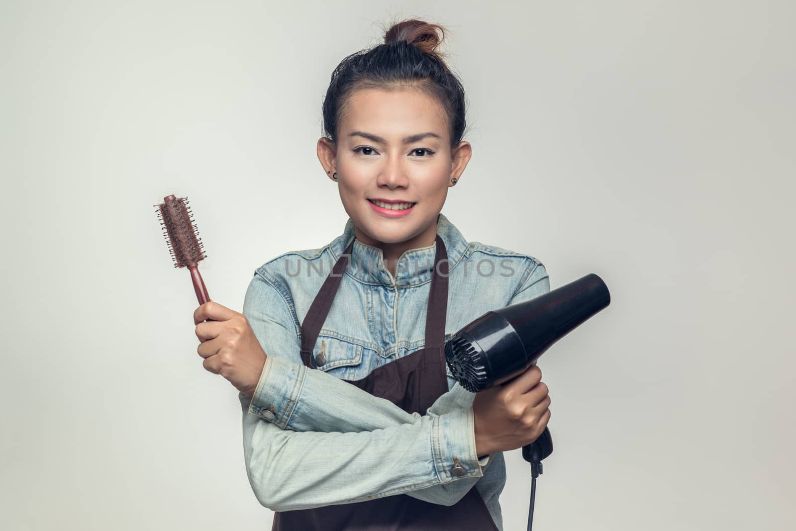 Asia woman was holding a hairdryer and brush. by PhairinThee