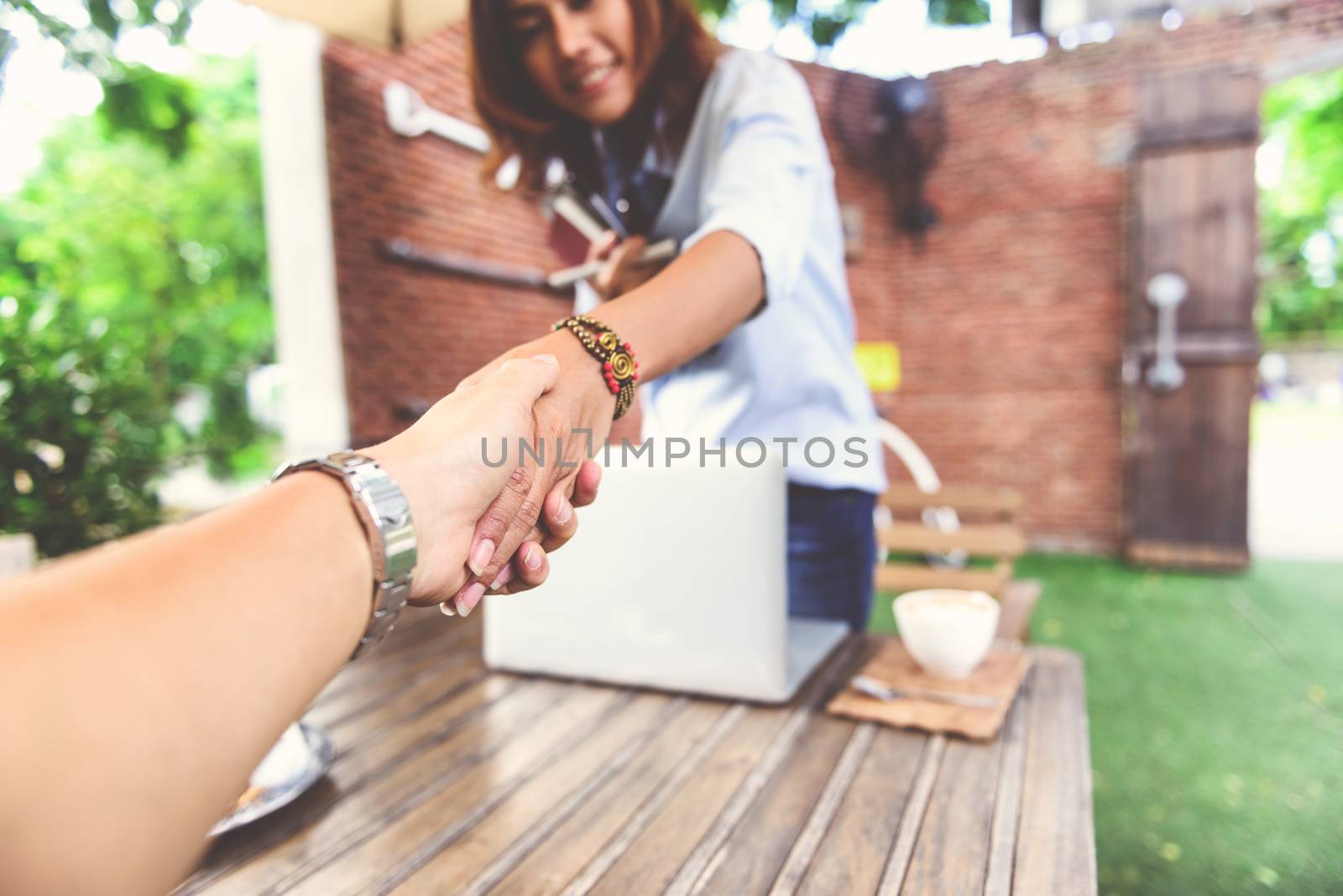 Photos of Asian women who are shaking hand by PhairinThee