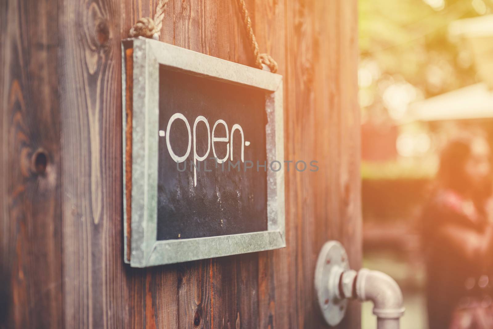 White 'Open' sign on black board with wooden door,Focus on letters