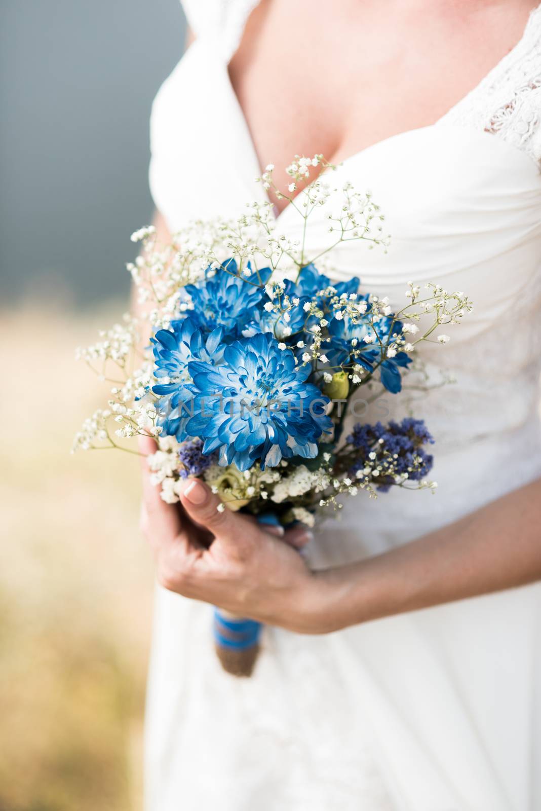 the bride holds a wedding bouquet with blue flowers