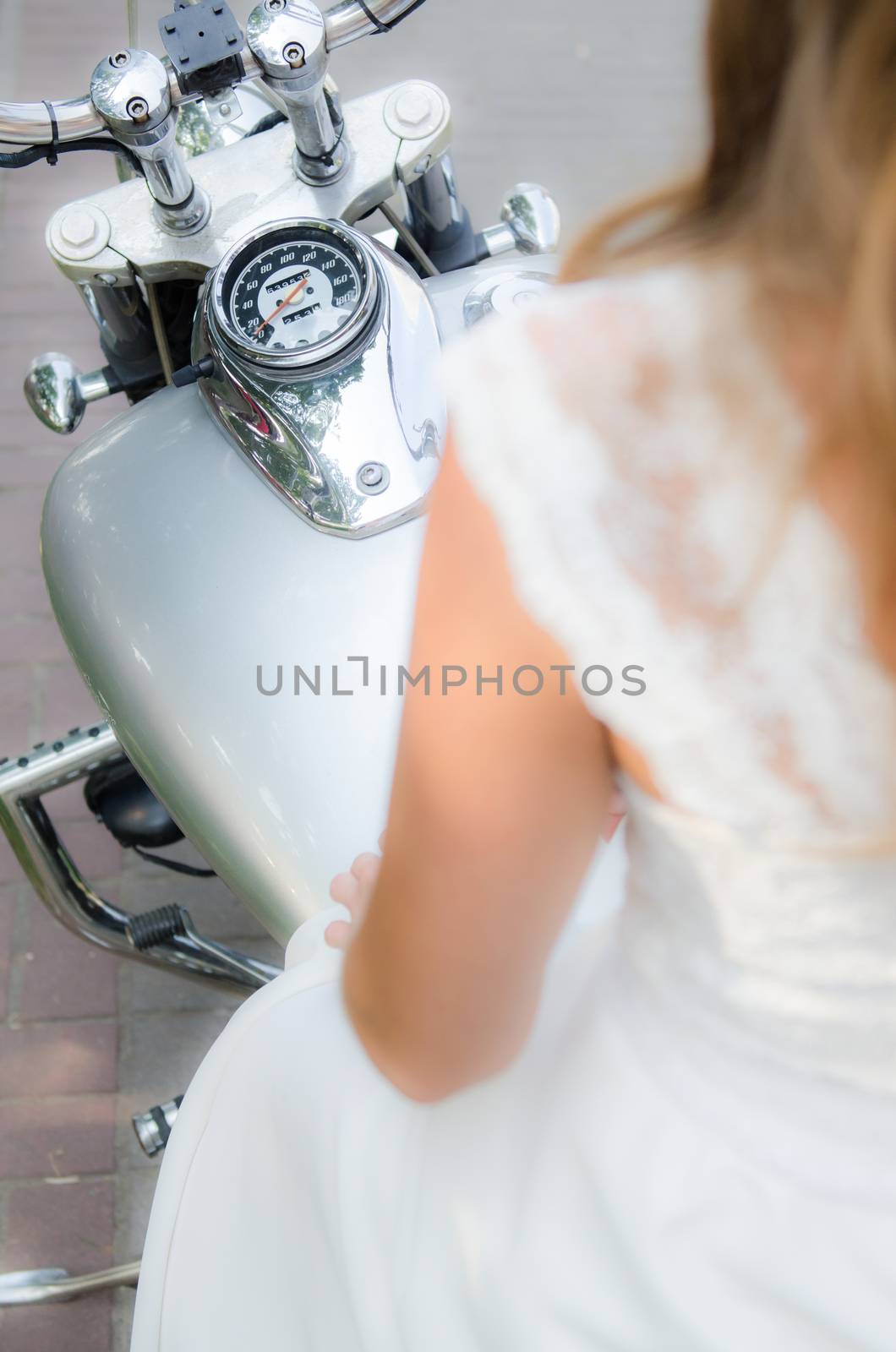the bride sits on a silver wedding motorcycle