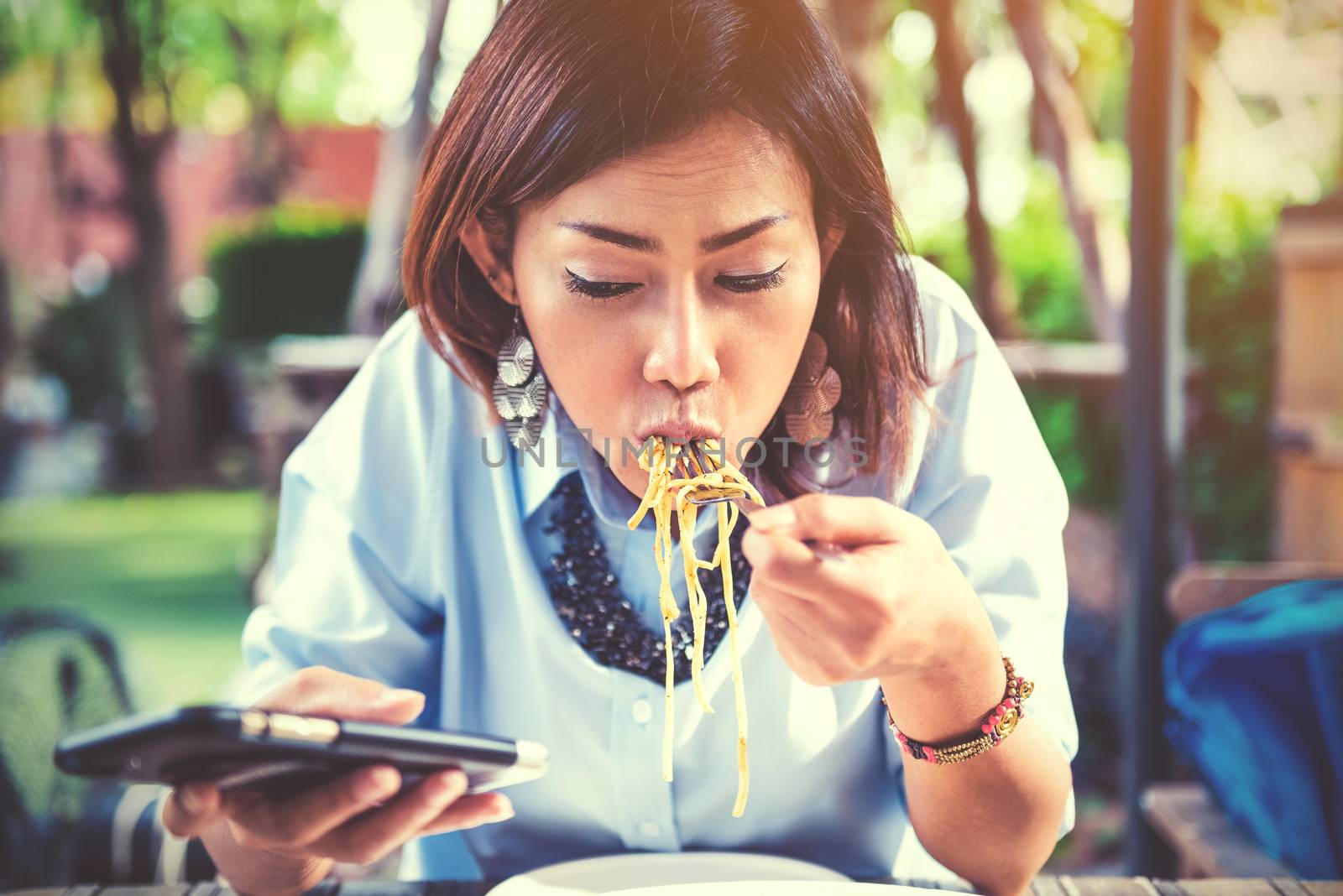 Asian women are happy when eating and playing mobile games,focus on the face.