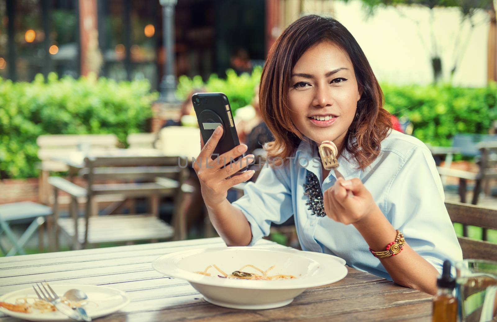 Asian women are happy when eating and playing mobile games by PhairinThee