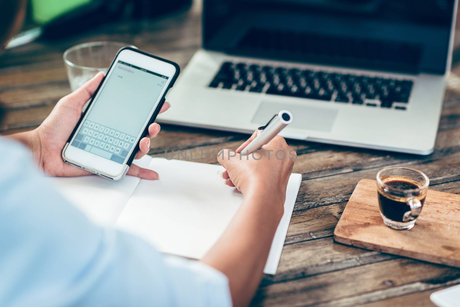 Woman taking notes on paper, focus on hands.